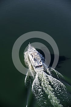 The yacht with decks and cabins cuts through the surface of the water leaving foamy white trail around