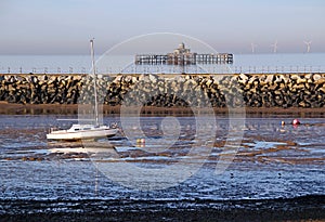 Yacht and derelict pier at low tide