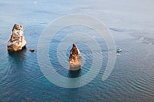 Yacht floating between stones. Deep and calm blue sea. Water tex