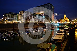 Yacht harbor surrounded by buildings and lights at night in Cologne, Germany