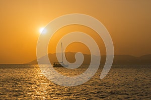 Yacht with lowered sail, sunset against the backdrop of mountains