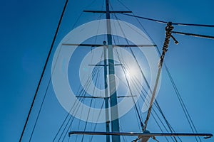 Yacht mast against the blue sky with sun glare