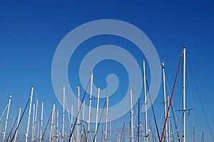 Yacht masts without sails against the background of a clear blue sky, copy space