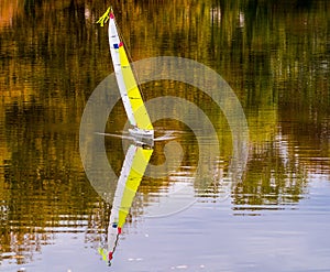 Yacht model symmetrically reflected on water surface of lake