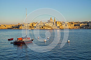 A yacht moored in the Marsamxett harbor with the Valletta capital city on the background. Malta