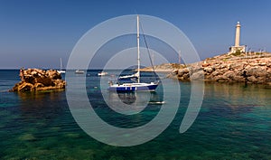 A yacht and other small boats, floating on a clear, aqua marine sea, off the coast of southern Spain