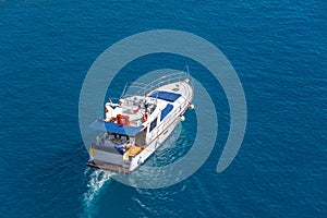 Yacht with passengers sun loungers at the stern floating on the water surface in summer