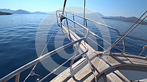 The yacht quickly sails across the blue sea towards the small islands on a clear sunny day. The bow of the yacht closeup