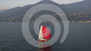 Yacht with red sail on the Garda Lake. Italy