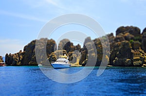 Yacht, rocks and blue sea, selective focus, effect tilt-shift