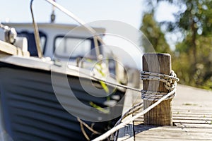 Yacht on a rope at the pier. Sea vessel is moored to an old wooden pier on a sunny summer day.