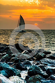 Yacht sailing against sunset. Holiday lifestyle landscape with skyline sailboat and sunset silhouette