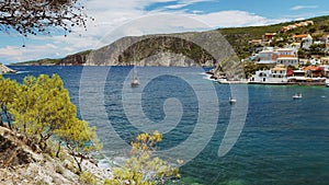 Yacht sailing boat in sea bay in hot summer. Greece assos village and shore coast of Kefalonia island in background