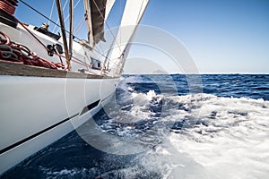 Yacht sailing fast on sea with waves towards island in Italy