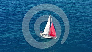 Yacht sailing on open sea at sunny day. Sailing boat with a red sail.