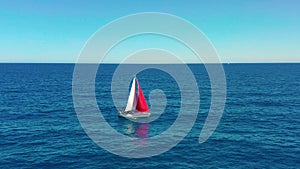 Yacht sailing on open sea at sunny day. Sailing boat with a red sail.