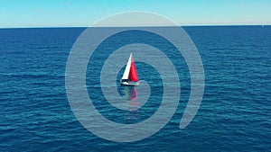 Yacht sailing on open sea at sunny day. Sailing boat with a red sail.