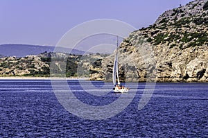 Yacht sailing towards a rocky island