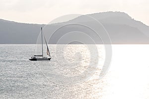 Yacht sailing towards the sun, Cape Panwa, Phuket, Thailand