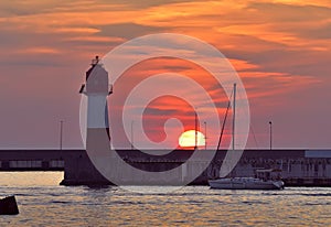 Yacht at the sea lighthouse at sunset