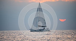 Yacht in the sea at sunset. Sailing in the sunrise time with sailboat. Landscape of sea and tropical beach. Beautiful