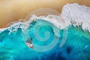 Yacht on the sea from top view. Turquoise water background from top view. Beach and waves. Summer seascape from air.