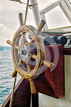Yacht steering wheel and binoculars vertical close up view on sea background