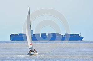 Yacht under Sail with large container ship