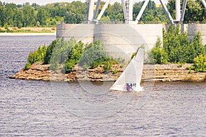 Yacht with white sails at Volga river. Sailboat tilted in a gust of wind. Boat with a sail is sinking