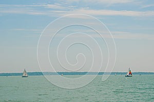 Yachting competition on Lake Balaton, Hungary. Two sailing boats on foreground under beautiful blue sky with clouds