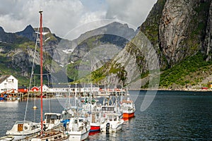 Yachts and boats with mountains in the background at pier in Reine, Moskenesoya, Lototen islands,, Nordland County, Norway