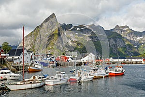 Yachts and boats with mountains in the background at pier in Reine, Moskenesoya, Lototen islands,, Nordland County, Norway photo