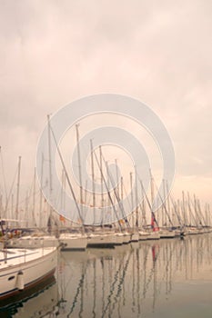 Yachts and boats are at the pier in the morning in the fog.