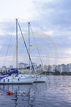 Yachts with high masts and lowered sails on the background of urban buildings