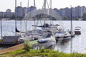 Yachts with high masts and lowered sails on the background of urban buildings