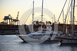 Yachts and motor boats in La Marina de Valencia. Luxury yacht and fishing motorboat in yacht club on sunset. Skiff and Sailboat in