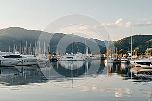 Yachts are preparing to sail in port at sunset on background of