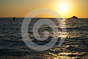 Yachts sail on the sea near a sunny path at sunset. View from the Kabak beach in Turkey.