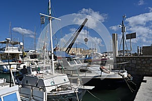 Yachts, sailing boats and old wooden boats with white hulls in Greek port of Heraklion.