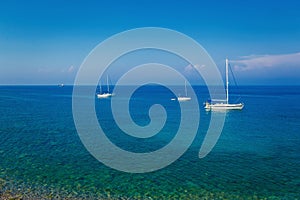 Yachts sailing in a Mediterranean sea on a clear sunny day, Greece. Blue sky with white clouds. Idyllic seascape.