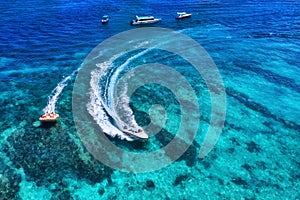 Yachts at the sea in Bali, Indonesia. Aerial view of luxury floating boat on transparent turquoise water at sunny day. Summer seas