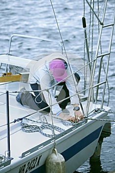 Yachtsman holds ropes in hands knitting a knot on a upper deck of yacht during mooring