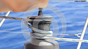 Yachtsman rotates the halyard winch with yacht ropes