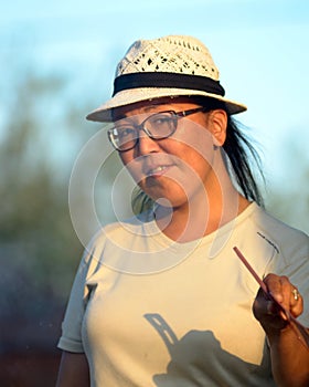 Yakut Asian girl in glasses and hat waving her fan in the rays of the setting sun