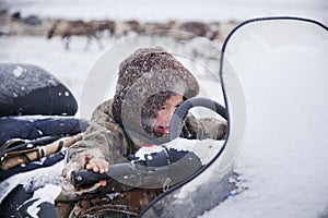 The Yamal Peninsula. Happy boy on reindeer herder pasture plays outside on a cold winter day, the boy is sitting behind the wheel