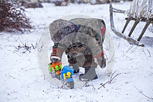 The Yamal Peninsula. Reindeer with a young reindeer herder. Happy boy on reindeer herder pasture playing with a toy motorcycle in