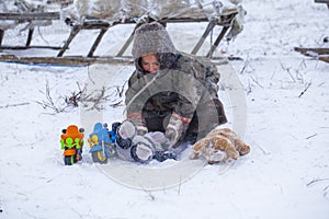 The Yamal Peninsula. Reindeer with a young reindeer herder. Happy boy on reindeer herder pasture playing with a toy motorcycle in