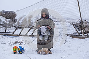 The Yamal Peninsula. Reindeer with a young reindeer herder. Happy boy on reindeer herder pasture playing with a toy motorcycle in