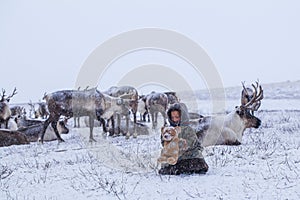 The Yamal Peninsula. Reindeer with a young reindeer herder. Happy boy on reindeer herder pasture playing with a toys in winter