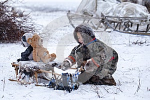 The Yamal Peninsula. Reindeer with a young reindeer herder. Happy boy on reindeer herder pasture playing with a toys in winter